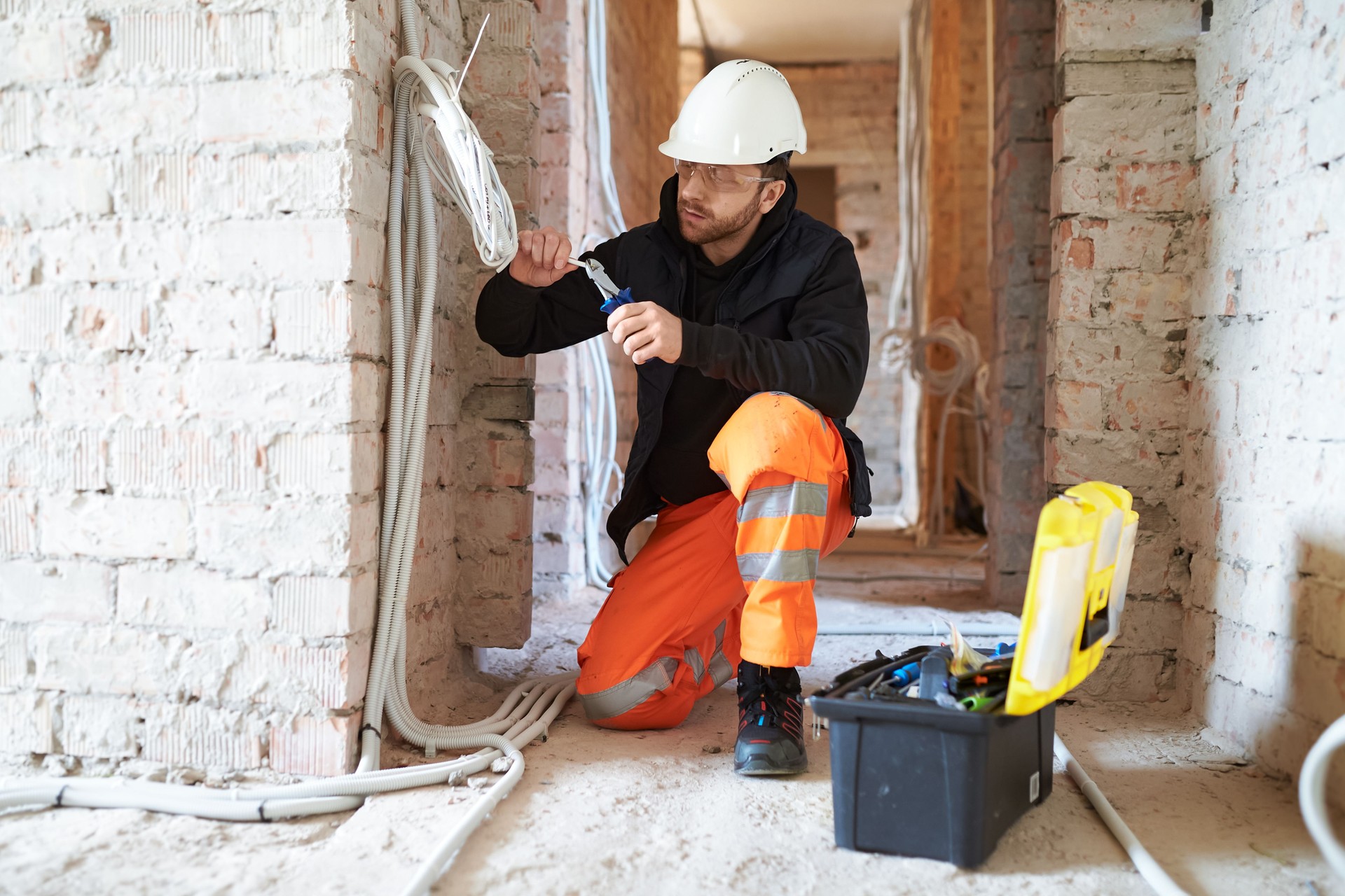 Electrical contractor working with cables on construction site.